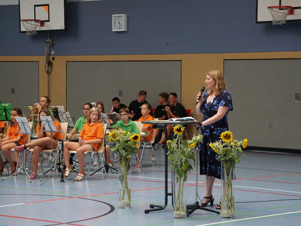 Zwei Personen sprechen vor dem Orchester.
